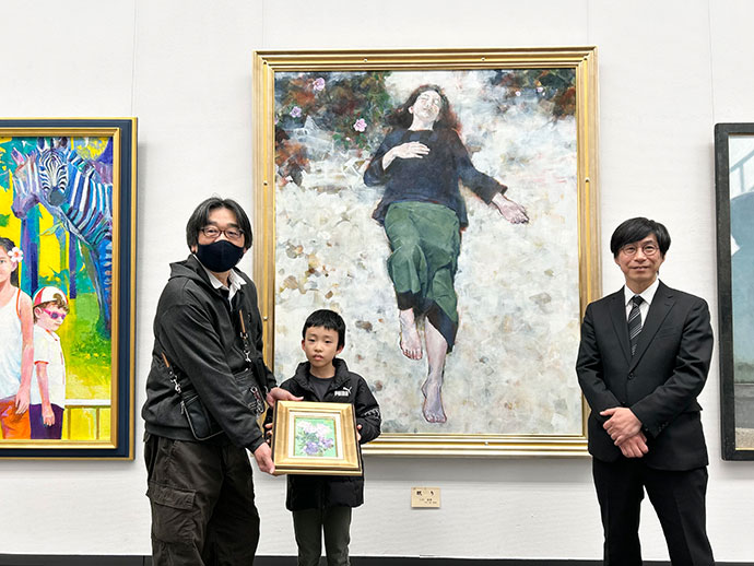 午後2時10分に来場した竹下なおやさん（小3）に洋画家の小川満章さんの画がプレゼントされました。
